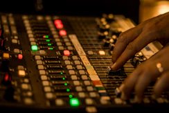 An audio engineer adjusting mixing console controls in a modern studio.