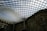 A large, curved glass roof structure covers a historic building, creating a modern architectural feature. The grid pattern of the glass panels allows natural light to filter through, casting a geometric shadow on the stone facade below.