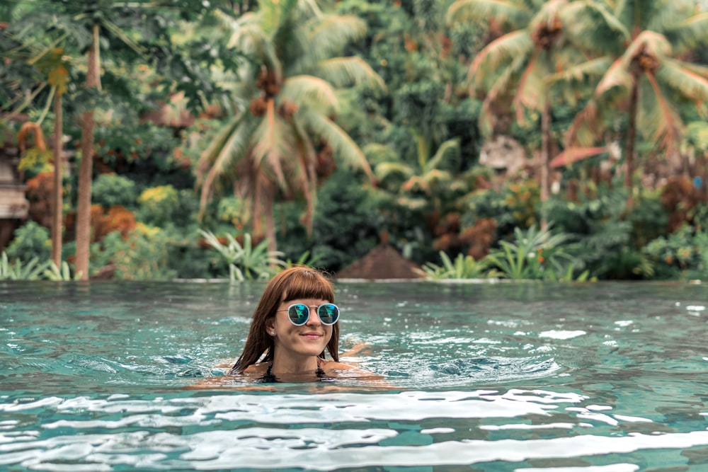 woman swimming on body of water during daytime