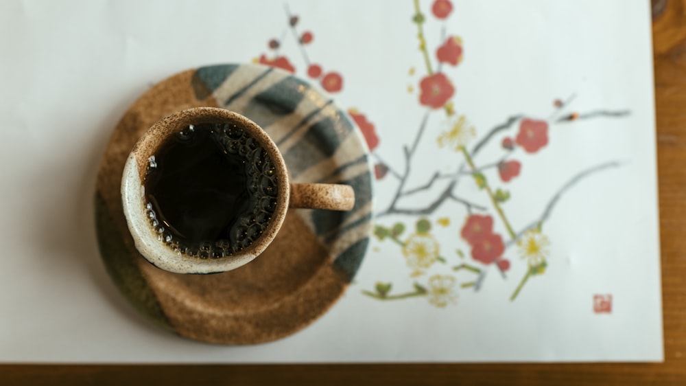 ソーサーにコーヒーを載せた茶色と白のマグカップ