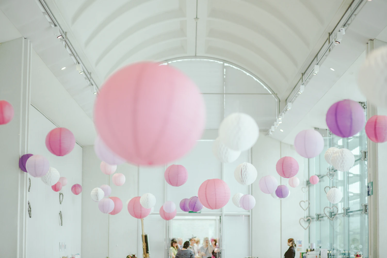 Pink, white, and purple paper lantern decorations suspended indoors