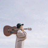 woman carrying brown acoustic guitar