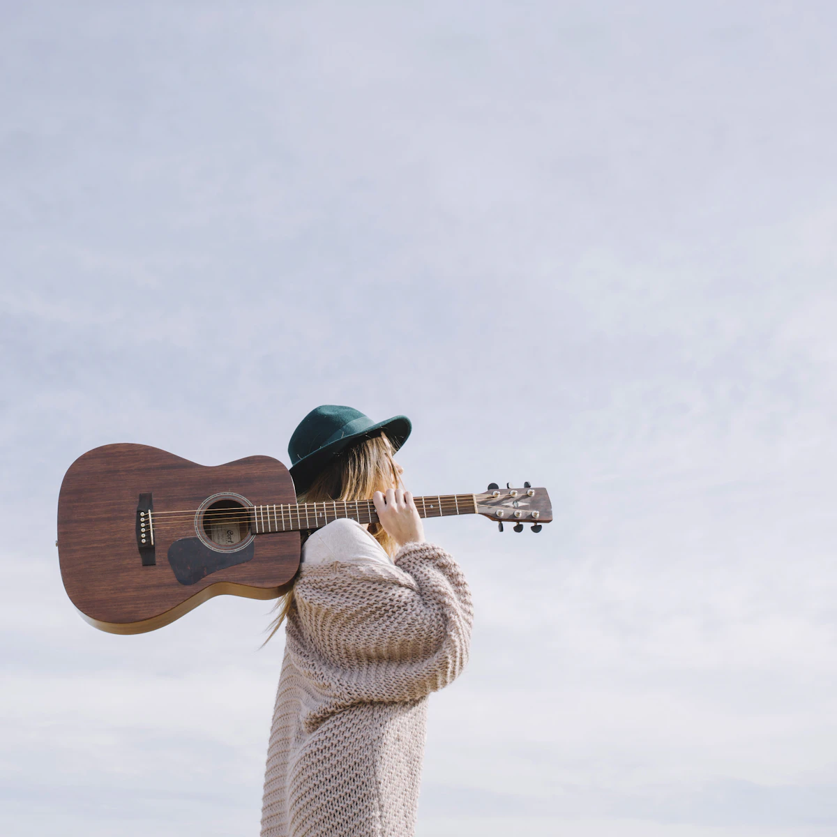 A musician holding an acoustic guitar outside