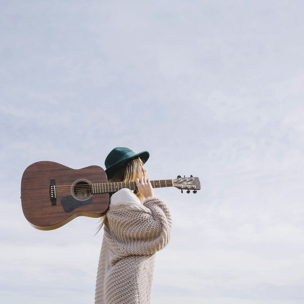 Frau trägt braune Akustikgitarre
