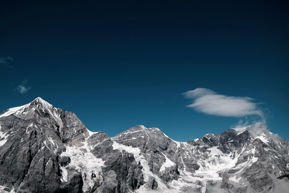 snow covered rocky mountain under clear sky at daytime