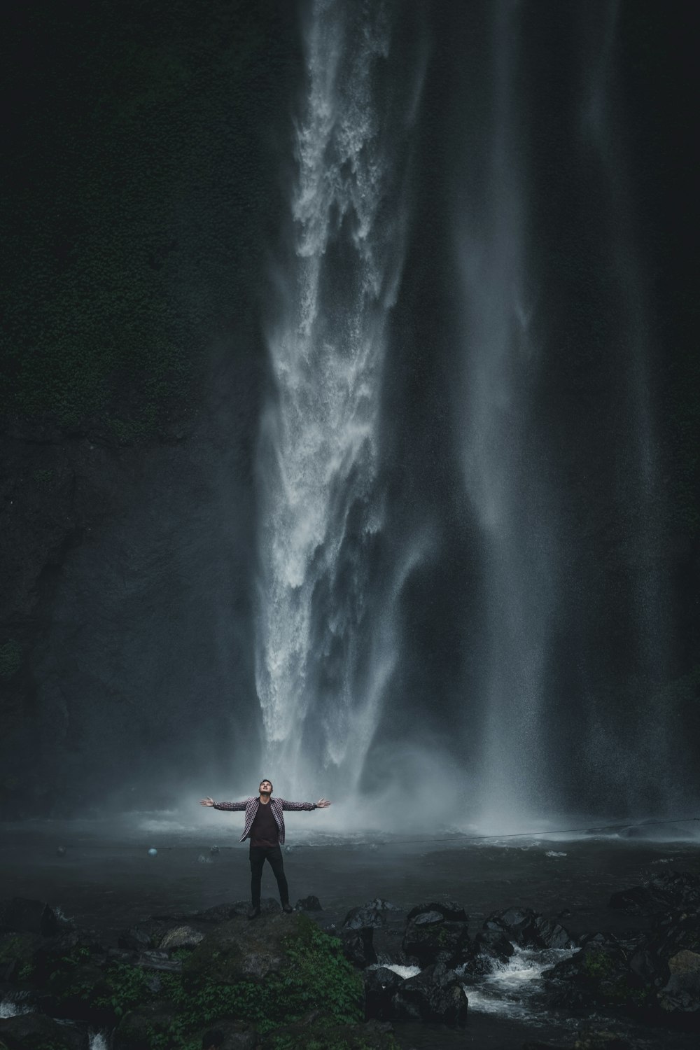 Mann in grauer Jacke steht in der Nähe von Wasserfällen