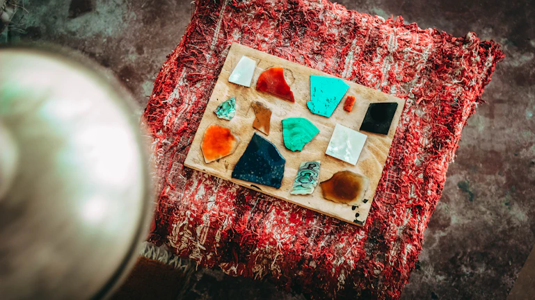 A collection of various stained glass panels displayed on a rustic wooden table.