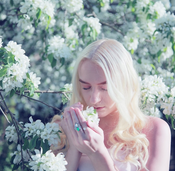 woman smelling flower during daytime