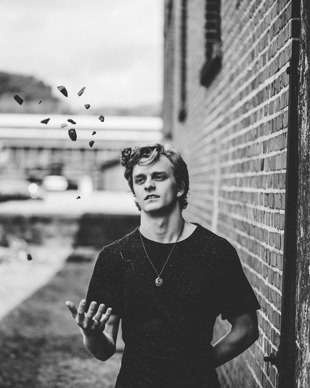 grayscale photo of man standing beside the wall