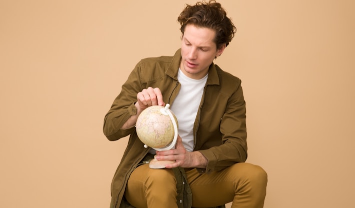 man holding globe while on sit