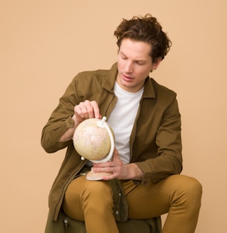 man holding globe while on sit