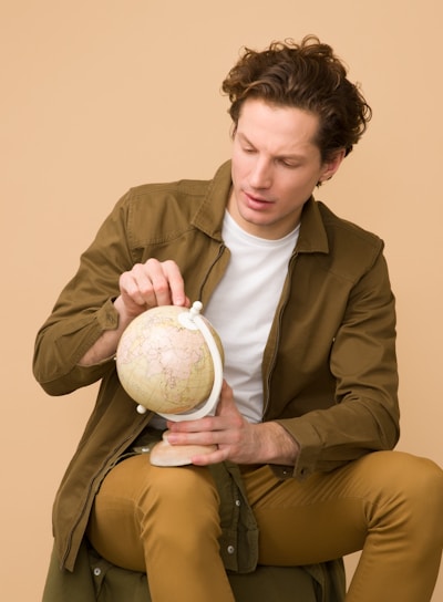 man holding globe while on sit