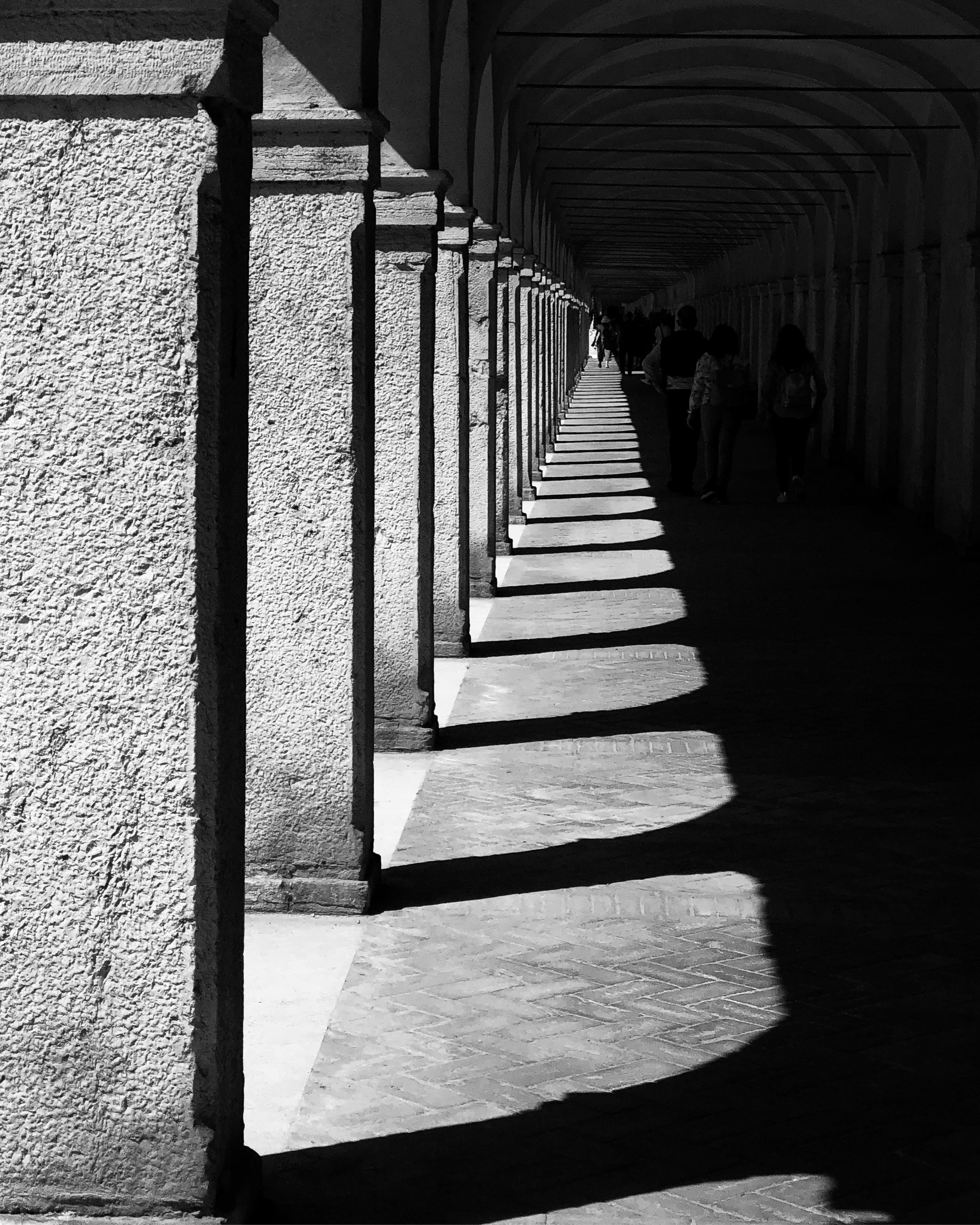People Walking Under Shade On Pillars And Building Ceiling At