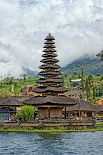 brown and black concrete building near body of water under cloudy sky