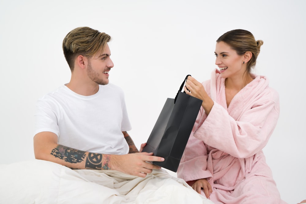 woman holding black paper bag sitting in front of the man