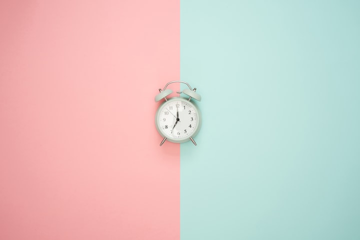clock laying on a pink and blue wallpaper 