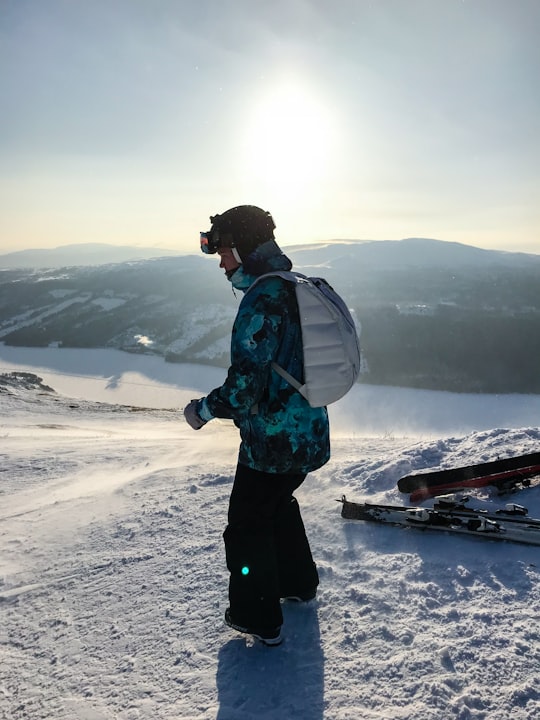 person with backpack standing on snow field looking down in Åre Sweden