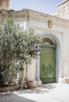 green wooden door is close of concrete building during daytime