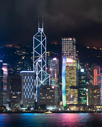A shimmering neon-lit cyberpunk skyline with towering skyscrapers under a rain-soaked night sky.