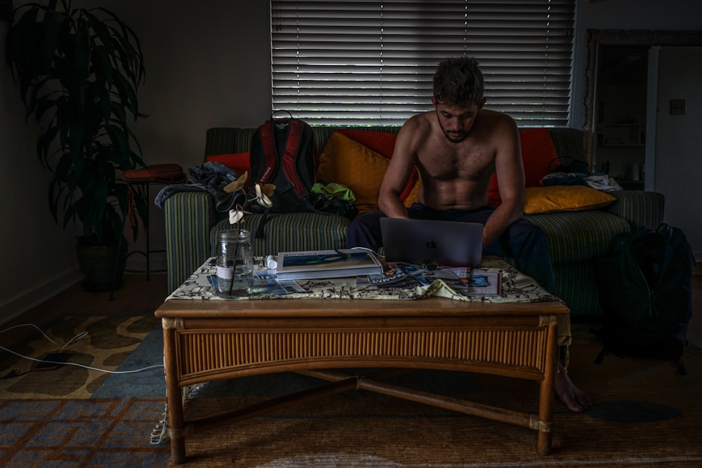 topless man front of laptop in living room set