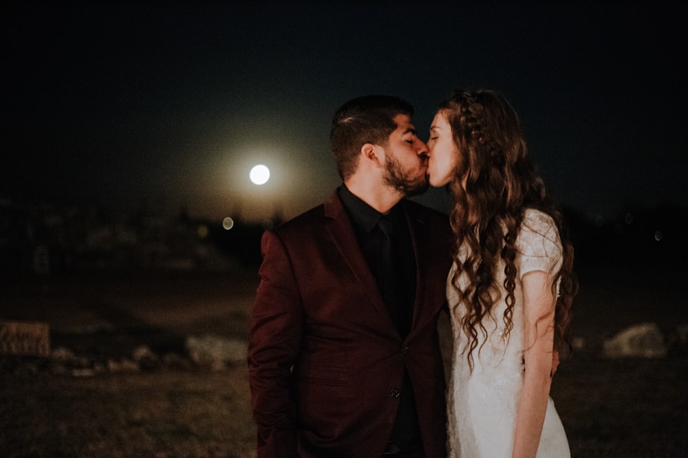 man kissing woman while standing