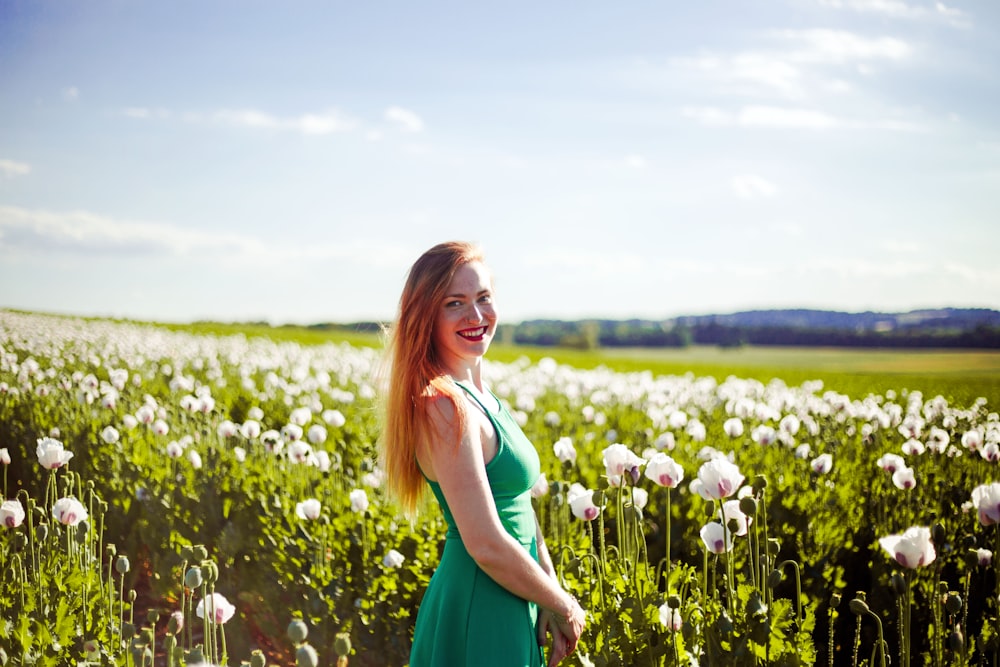 Femme debout près d’un champ de fleurs aux pétales blancs pendant la journée