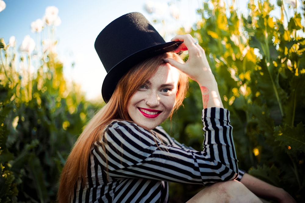 Mujer con sombrero de copa rodeada de plantas