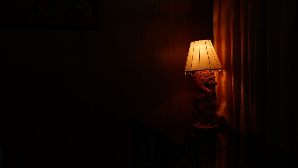 Fotografía de una lámpara de mesa iluminada cerca de una habitación oscura