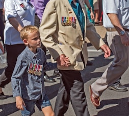 smiling man holding hand of boy while walking on road near people during daytime