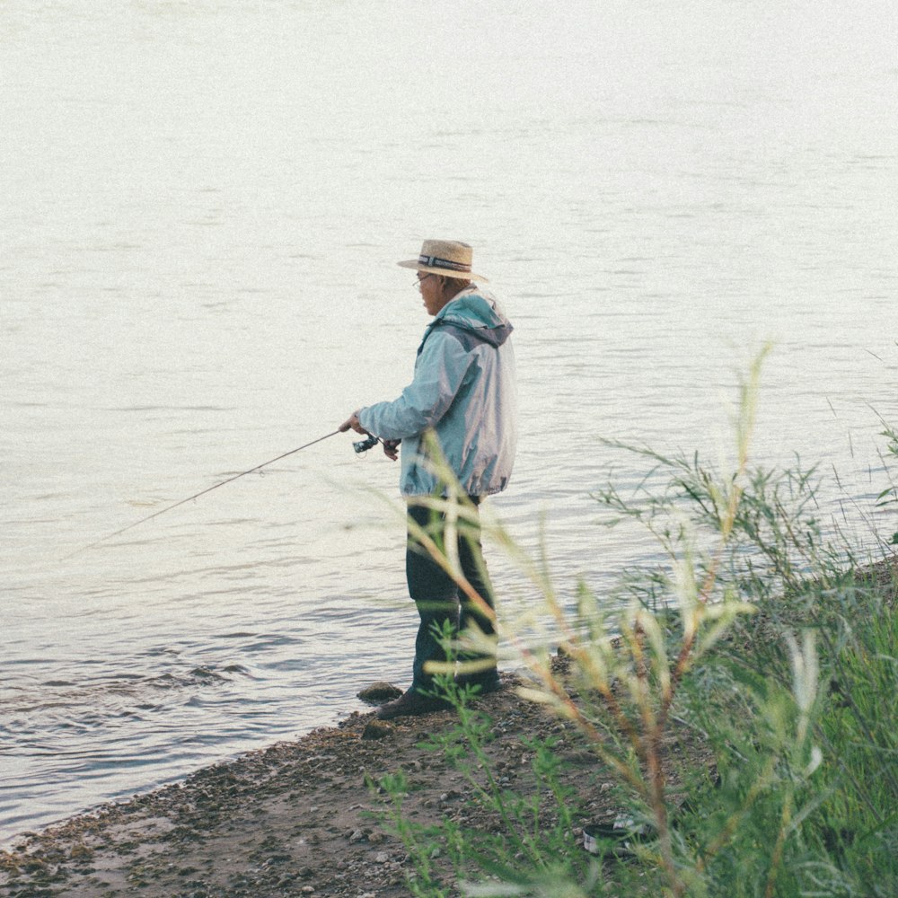 昼間の写真で水辺で釣りをする男