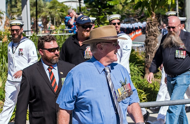 A group of veterans standing proudly together in a park, wearing military uniforms and medals.