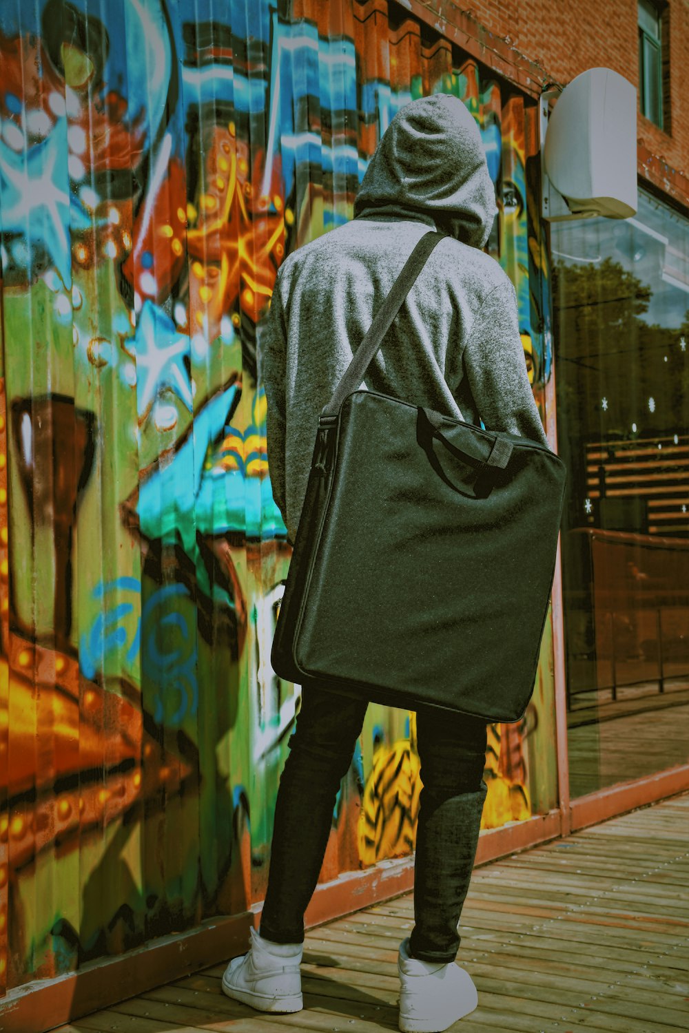 man wearing grey hoodie and black bag