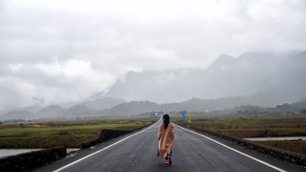 woman walks on gray concrete road during daytime