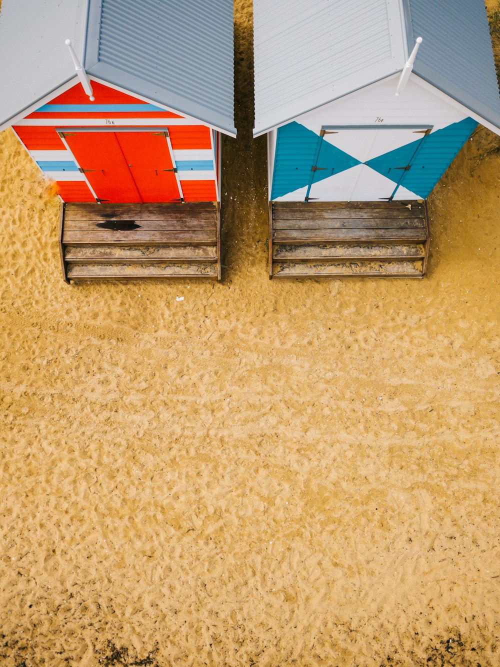 aerial photo of two blue and red wooden sheds on desert photo