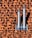 Two metallic chimneys are mounted on a textured orange and brown tile roof. The tiles have a gradient shading effect with shadows casted by the chimneys.