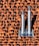 Two metallic chimneys are mounted on a textured orange and brown tile roof. The tiles have a gradient shading effect with shadows casted by the chimneys.