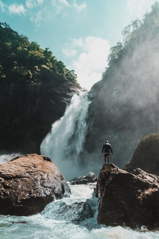 man standing stone with waterfalls in Dunhinda Falls Sri Lanka