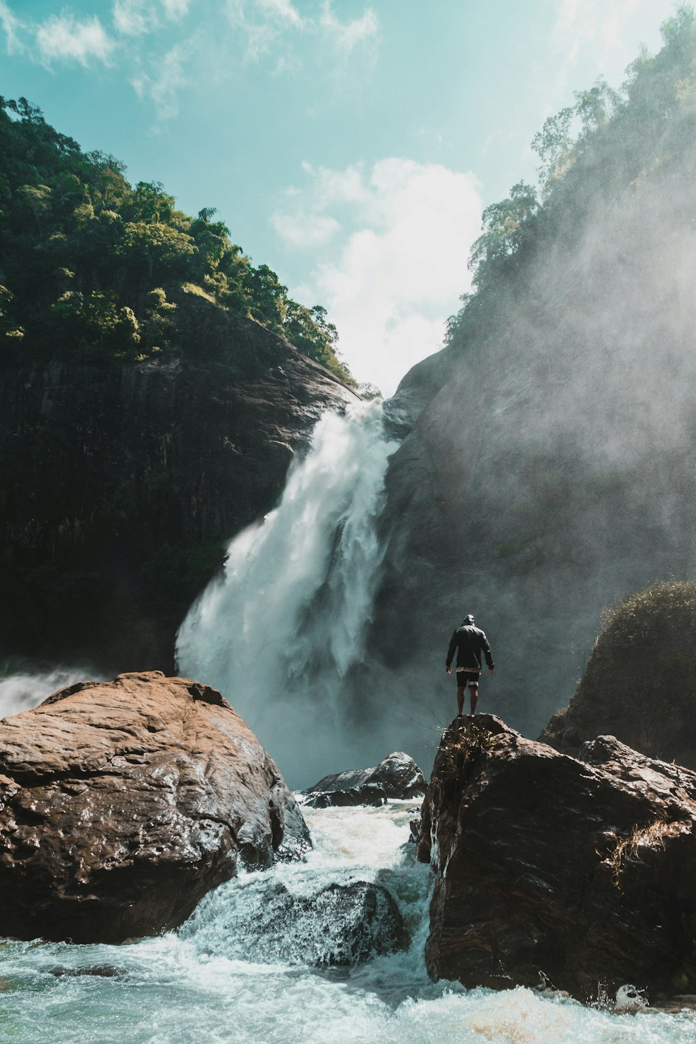 man standing stone with waterfalls