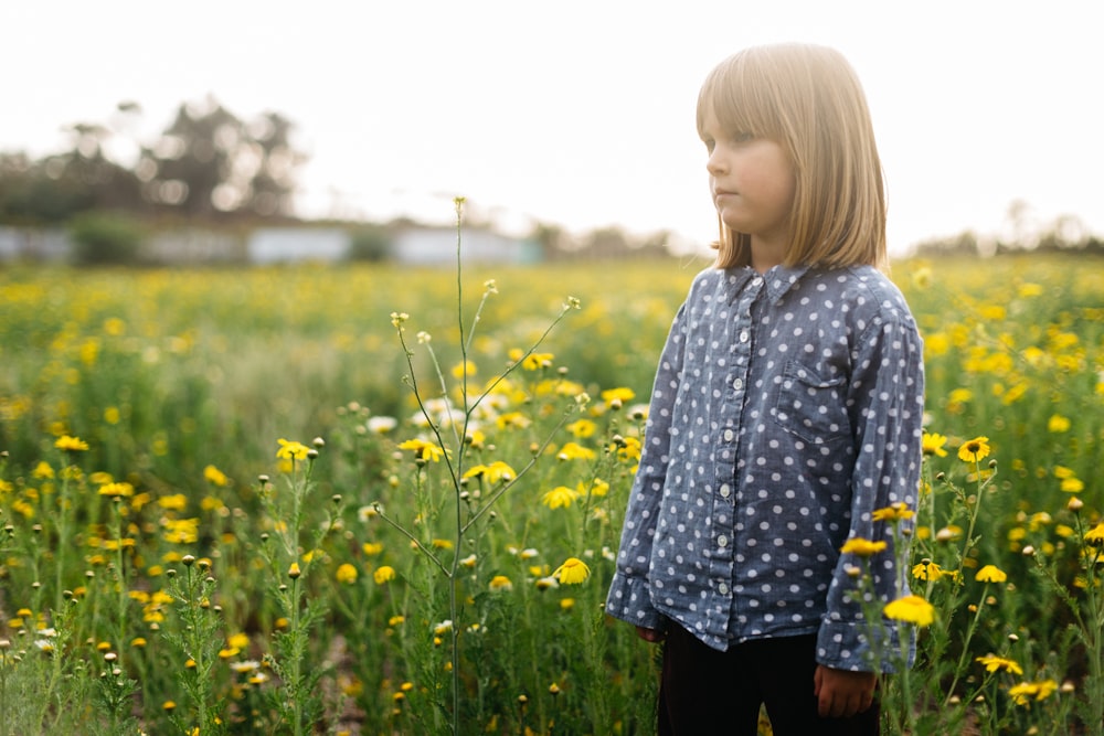 Ragazza in piedi circondata da fiori gialli durante il giorno