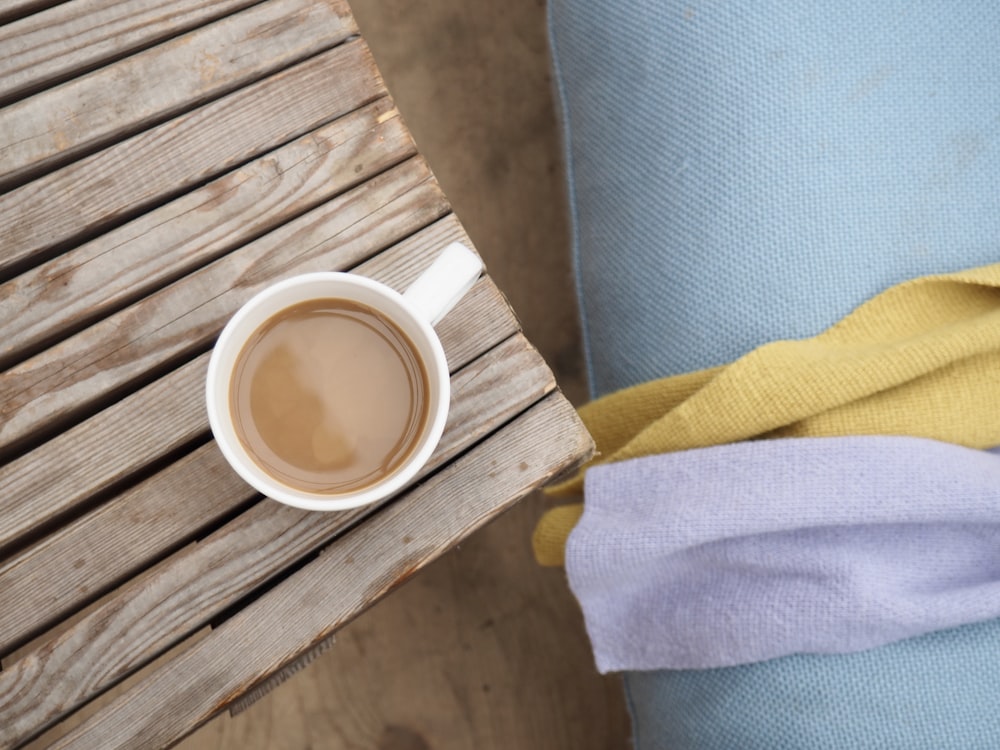 Kaffeegefüllter Keramikbecher auf brauner Holzplatte