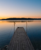 A wooden dock stretching into the still lake reflecting the soft evening sky.