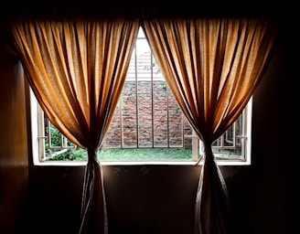 Luxurious velvet bedroom drapes hanging gracefully beside a sunlit window.