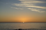 A serene sunset over the ocean with whales swimming nearby.