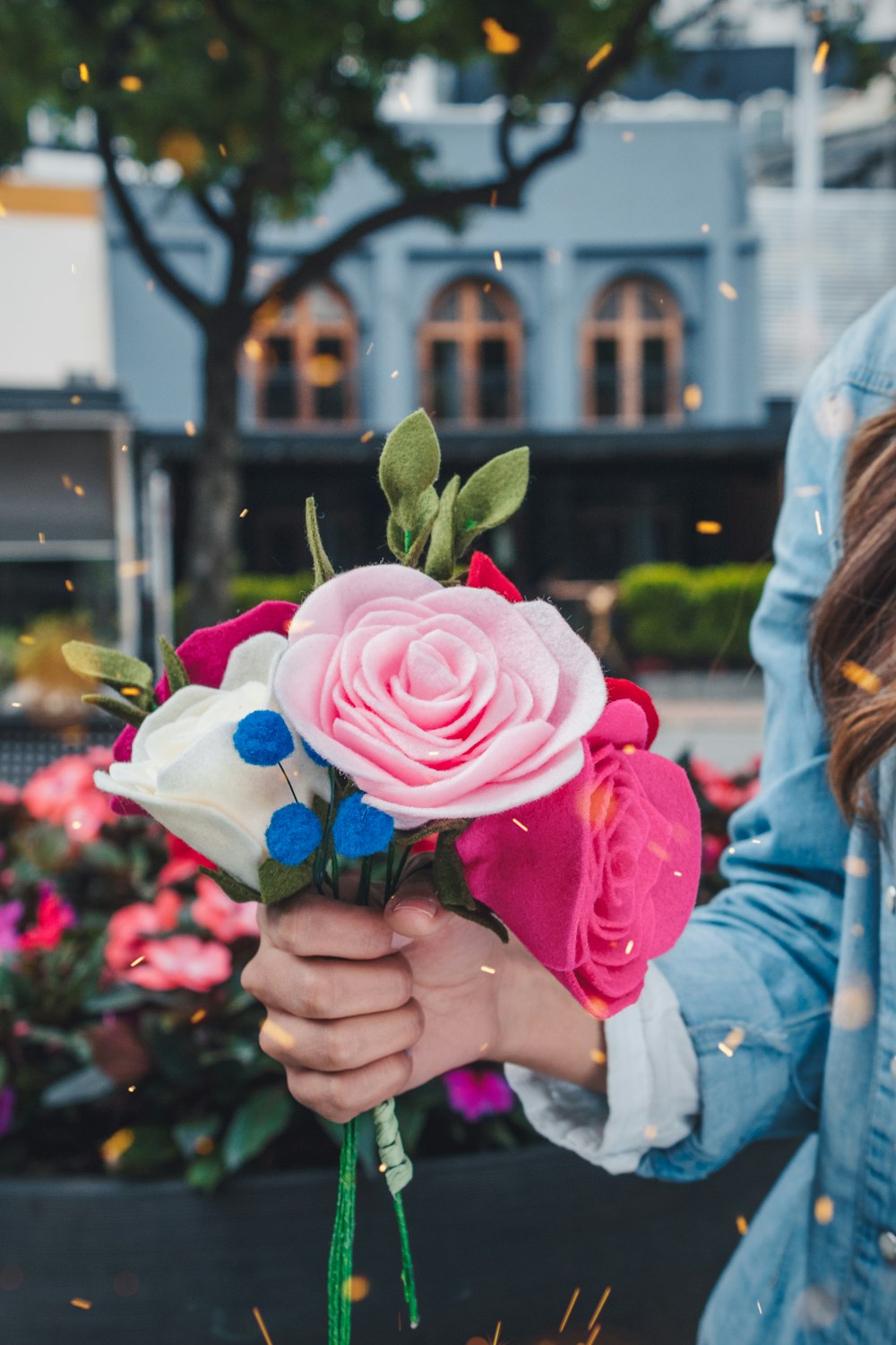 donna che tiene il fiore finto dai petali rosa e bianchi