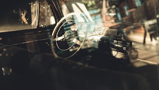 Photo of a car interior focusing on the steering wheel and dashboard with natural light.