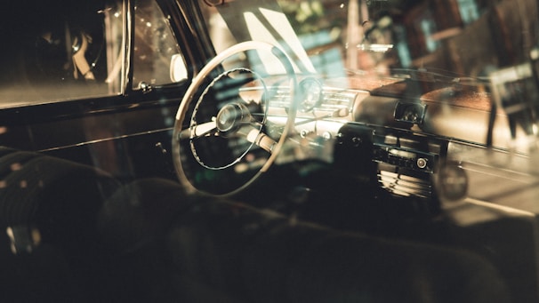 Photo of a car interior focusing on the steering wheel and dashboard with natural light.