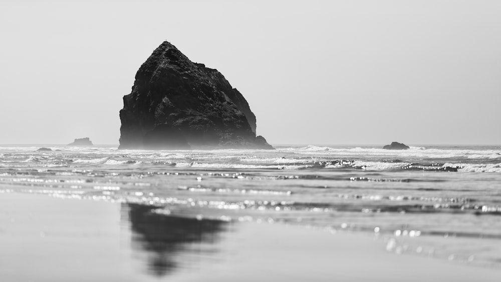 Foto en escala de grises de la formación rocosa en el mar