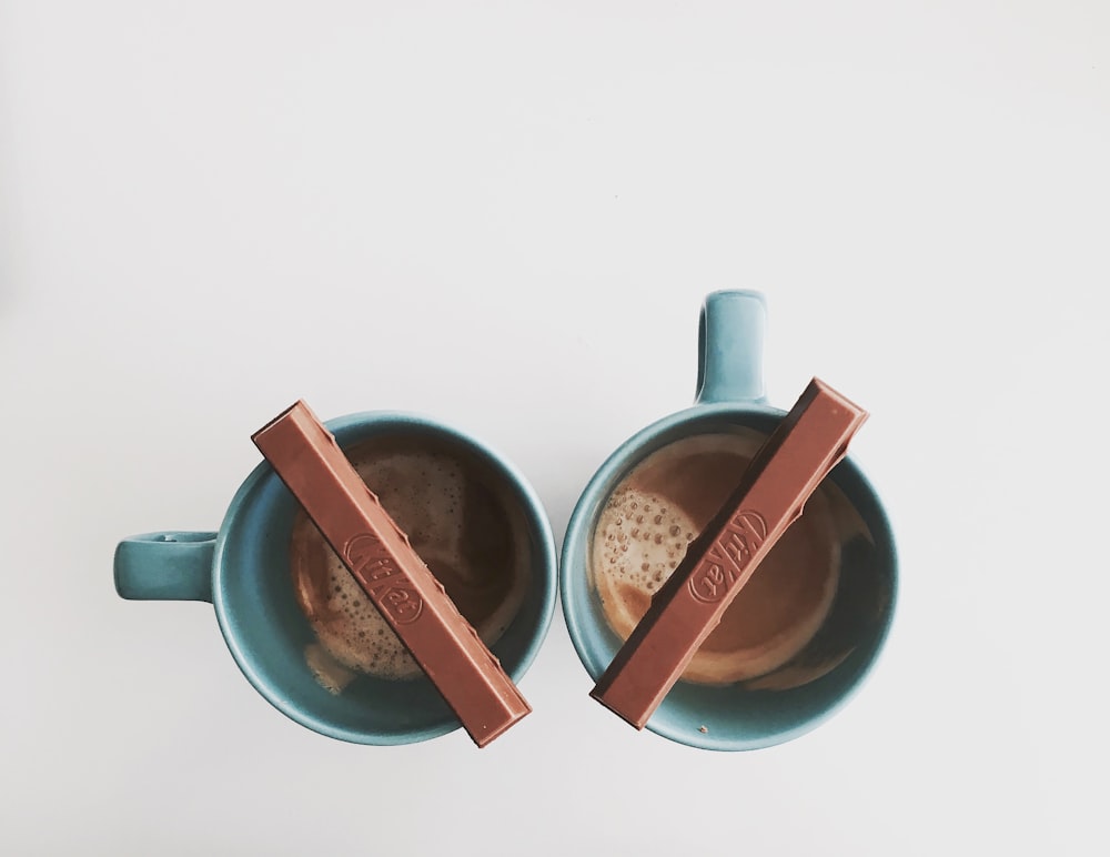 Dos tazas de cerámica verde con tableta de chocolate en la parte superior