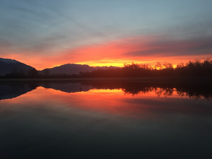 A stunning sunset over a tranquil lake reflecting vibrant colors.