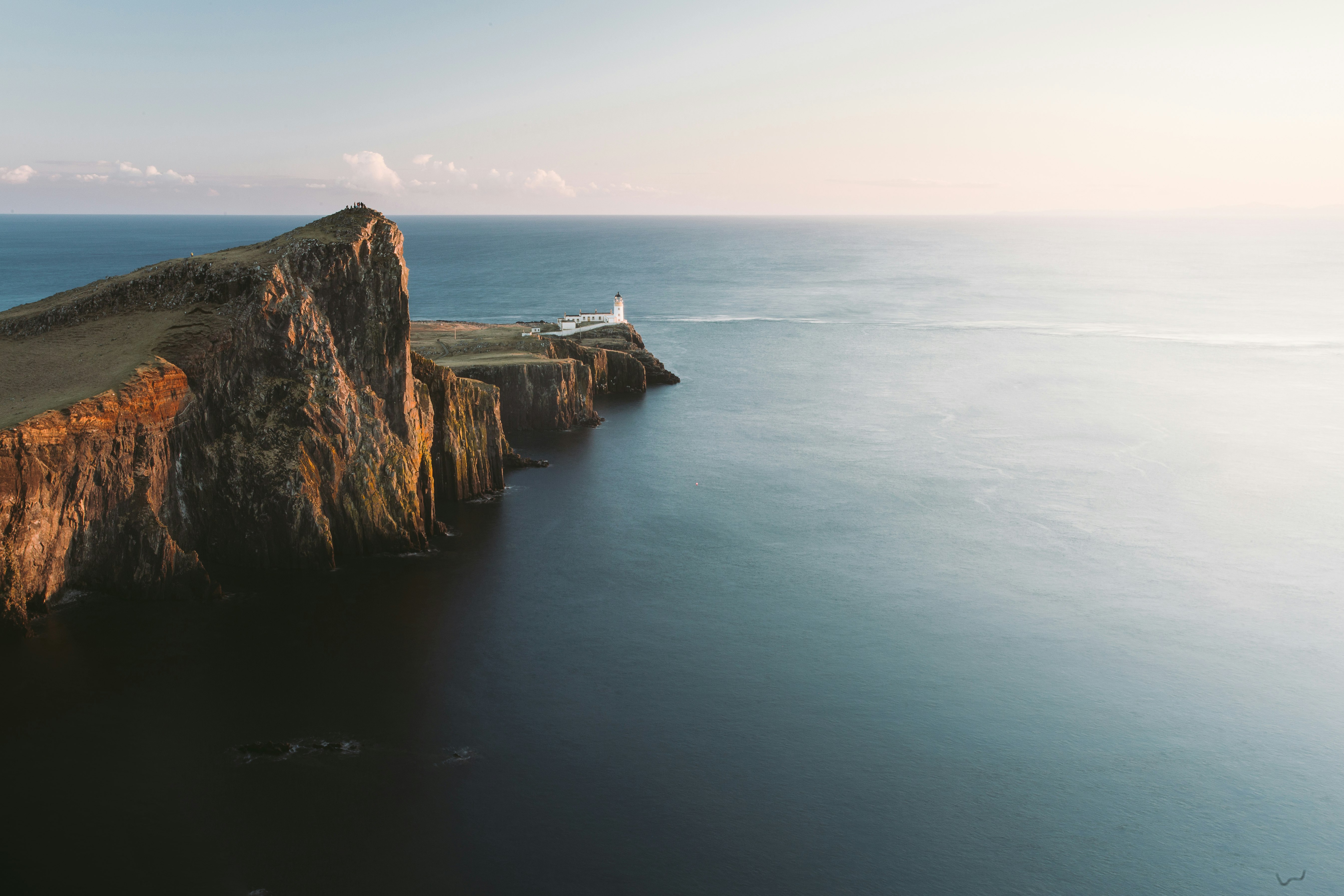 brown mountain cliff beside of blue ocean aerial photography
